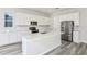Modern kitchen boasts white cabinets, stainless steel appliances, an island with quartz countertops and gray wood floors at 9951 Trellis Vine Way, Parrish, FL 34219