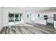 Bright open-concept living area featuring gray wood floors, and large sliding glass doors for natural light at 9951 Trellis Vine Way, Parrish, FL 34219