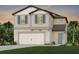 Two-story home featuring blue shutters, neutral siding, and a two-car garage, set against a twilight sky at 9959 Trellis Vine Way, Parrish, FL 34219