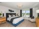 Stylish main bedroom with a blue accent bed, decorative pillows, and scenic view from the windows at 9959 Trellis Vine Way, Parrish, FL 34219