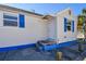 Exterior view of a beach home with blue trim, showing its entry, windows, and proximity to the water at 101 146Th Ave, Madeira Beach, FL 33708