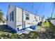 Exterior side view of a white cottage with blue trim, showing the structure and surrounding yard at 101 146Th Ave, Madeira Beach, FL 33708