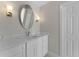 Bathroom with a white marble vanity, oval mirror, and modern lighting fixtures at 11050 7Th E St, Treasure Island, FL 33706