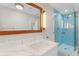 Bathroom with modern vanity, framed mirror and blue tiled shower at 11050 7Th E St, Treasure Island, FL 33706