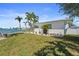 Waterfront home featuring lush landscaping, palm trees, and a serene water view at 11050 7Th E St, Treasure Island, FL 33706