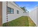 Side yard featuring green grass, a white fence, and a stylish rain chain at 11050 7Th E St, Treasure Island, FL 33706