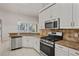 Well-equipped kitchen featuring stainless steel appliances, granite countertops, and white cabinets at 16119 Bridgedale Dr, Lithia, FL 33547