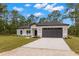 Modern single-story home boasts a two-car garage, manicured lawn, and contemporary design at 16431 Penn State Rd, Weeki Wachee, FL 34614