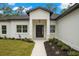 Close-up of home's entrance featuring a modern black door, manicured landscaping, and accent lighting at 16431 Penn State Rd, Weeki Wachee, FL 34614