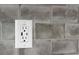 A close-up of a wall outlet surrounded by gray tiles at 16431 Penn State Rd, Weeki Wachee, FL 34614