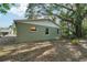 View of the backyard with green home and a large shade tree at 1720 W Arch St, Tampa, FL 33607