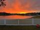 Scenic lake view at sunset with a white fence in the foreground at 19112 Cypress Green Dr, Lutz, FL 33558
