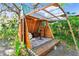 Exterior view of small outbuilding with wood frame, green roof, and patio with furniture and lush landscaping at 201 Gornto Lake Rd, Brandon, FL 33510