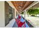 Spacious front porch with red rocking chairs, offering ample outdoor seating and a view of the yard at 201 Gornto Lake Rd, Brandon, FL 33510
