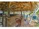 Outdoor tiki bar features a cozy space for entertaining in a tropical setting, complete with seating and a thatched roof at 208 44Th Ne Ave, St Petersburg, FL 33703