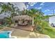 Outdoor tiki bar with stools and thatched roof, surrounded by tropical plants and the edge of a swimming pool at 208 44Th Ne Ave, St Petersburg, FL 33703