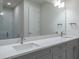 Bright bathroom featuring double sinks with gray cabinets, white countertops, and a large mirror at 2529 Mario Way, Clearwater, FL 33761