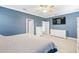 Bright bedroom featuring blue walls, white trim, a white dresser, and a large television at 3204 Mapleridge Dr, Lutz, FL 33558