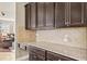 View of the butlery featuring dark cabinets and light granite countertops at 3204 Mapleridge Dr, Lutz, FL 33558