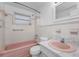 Bathroom with original pink tile and bathtub and a marble sink at 4920 Zodiac Ave, Holiday, FL 34690