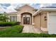 Inviting front entrance featuring double doors, arched window, and manicured landscaping at 617 Glastonbury Ct, Spring Hill, FL 34609