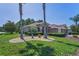 Landscaped front lawn featuring palm trees, garden bed, and a single-story home with neutral colors at 617 Glastonbury Ct, Spring Hill, FL 34609
