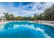 Community pool with blue water surrounded by lounging chairs and lush landscaping at 617 Glastonbury Ct, Spring Hill, FL 34609