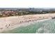 Beautiful beach scene with clear turquoise water, relaxing beachgoers, and nearby colorful buildings at 7050 Sunset Way # 22, St Pete Beach, FL 33706
