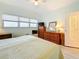 Bright bedroom with light green walls, wood flooring, large windows, ceiling fan and wood dresser at 7050 Sunset Way # 22, St Pete Beach, FL 33706
