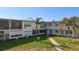 Exterior of the condo building featuring a well-maintained lawn, patio, and tropical landscaping at 7050 Sunset Way # 22, St Pete Beach, FL 33706