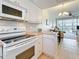 Bright kitchen with white cabinets, oven, microwave, and adjoining dining and living areas at 7050 Sunset Way # 22, St Pete Beach, FL 33706