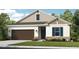Charming single-Gathering home featuring a two-car garage, manicured lawn, and a blend of stone and neutral siding at 731 Sky Shade Dr, Apollo Beach, FL 33572