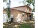 Side view of a two-story tan home with stone foundation accent and a fenced yard at 771 Murphy N Ave, St Petersburg, FL 33703