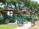 Community playground featuring a slide, green railings, and shady trees and umbrellas at 771 Murphy N Ave, St Petersburg, FL 33703