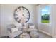 Cozy sitting area with decorative clock, comfortable chairs, patterned ottomans, and a scenic outdoor view at 9954 Trellis Vine Way, Parrish, FL 34219