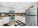 Retro kitchen design featuring black and white checkerboard floor, stainless appliances, and light wood cabinets at 1 Key Capri # 608E, Treasure Island, FL 33706