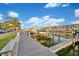 Dockside view of boats docked along a marina with a wooden boardwalk, palm trees, and residential buildings at 1 Key Capri # 608E, Treasure Island, FL 33706