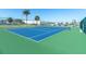 Outdoor community tennis court with a blue and green surface surrounded by a chain-link fence and marina in the background at 1 Key Capri # 608E, Treasure Island, FL 33706