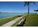 Relaxing outdoor bench overlooking the water with a paved walkway, lush landscaping and palm trees at 1 Key Capri # 608E, Treasure Island, FL 33706