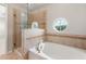 Bathroom boasts a soaking tub, separate glass shower, and decorative round windows for natural light at 10144 Arbor Run Dr # 139, Tampa, FL 33647