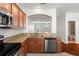 A well-equipped kitchen with stainless steel appliances, wood cabinets, granite countertops, and a view to the living area at 10144 Arbor Run Dr # 139, Tampa, FL 33647