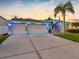 Charming home featuring a three-car garage, palm trees, manicured lawn, and vibrant blue lights creating inviting curb appeal at 10213 Lockwood Pines Ln, Tampa, FL 33635