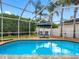 Enclosed pool area featuring clear blue pool water, lounge chairs, umbrella, and a screened-in enclosure at 10213 Lockwood Pines Ln, Tampa, FL 33635
