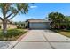 Well-maintained single-story home with a lush lawn, mature trees, and a two-car garage under a clear blue sky at 1040 Summer Breeze Dr, Brandon, FL 33511