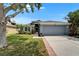 Charming single-story home with a well-maintained lawn, mature trees, and a two-car garage on a sunny day at 1040 Summer Breeze Dr, Brandon, FL 33511