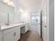 Bright bathroom with double sinks, vanity, modern fixtures, white cabinets, and wood-look tile flooring at 10446 Tupper Cay Dr, San Antonio, FL 33576