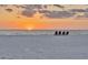 Sunset view over a sandy beach landscape with ocean waves and four Adirondack chairs at 1058 Eldorado Ave, Clearwater Beach, FL 33767