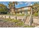 Two-story beachfront home with a balcony, lush lawn, and access stairs at 1058 Eldorado Ave, Clearwater Beach, FL 33767