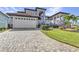Beautiful two-story home with a manicured lawn and a brick driveway leading to the garage at 107 Sunset Dr, Nokomis, FL 34275