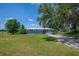 Exterior shot of a blue home with a red front door, blue skies, and surrounding trees at 11015 S County Road 39, Lithia, FL 33547